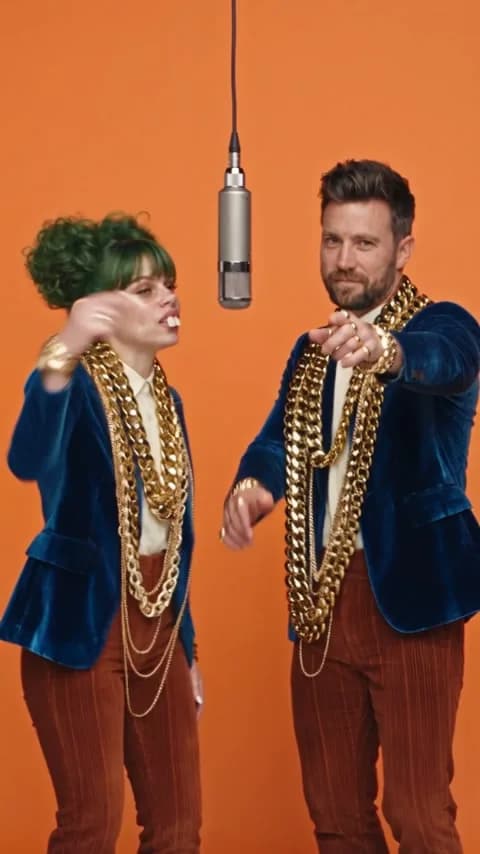 KI-Figur und Kai mit Goldketten vor orangem Hintergrund, KI-Video