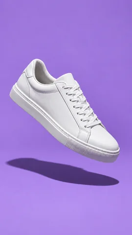 Weißer Turnschuh schwebt vor lila Hintergrund